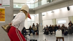 Eine Person mit Schnabelmaske
                                          schaut hinter einer Säule im Atrium der Universität für angewandte Kunst Wien hervor.