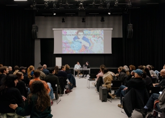 Richard Hawkins im Gespräch mit Christian Liclair an
                                          einem Tisch in einer Eventhalle