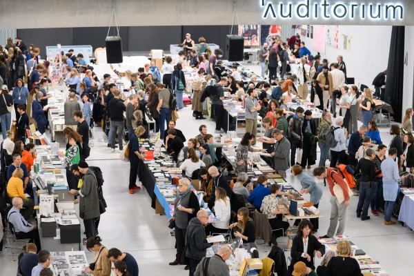 Atrium der Universität für Angewandte Kunst Wien während der Art Book Fair, gefüllt
                                          mit Menschen und Messeständen