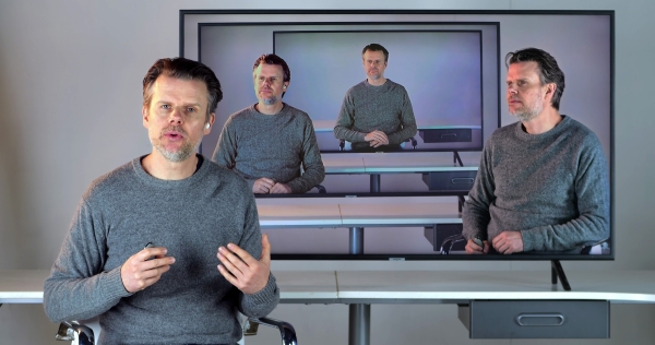 A man appears on the screens four times, and at one point seems to be speaking directly to the viewer.