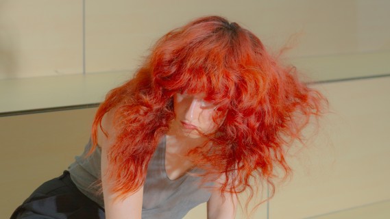 A person with red hair is kneeling on the ground.